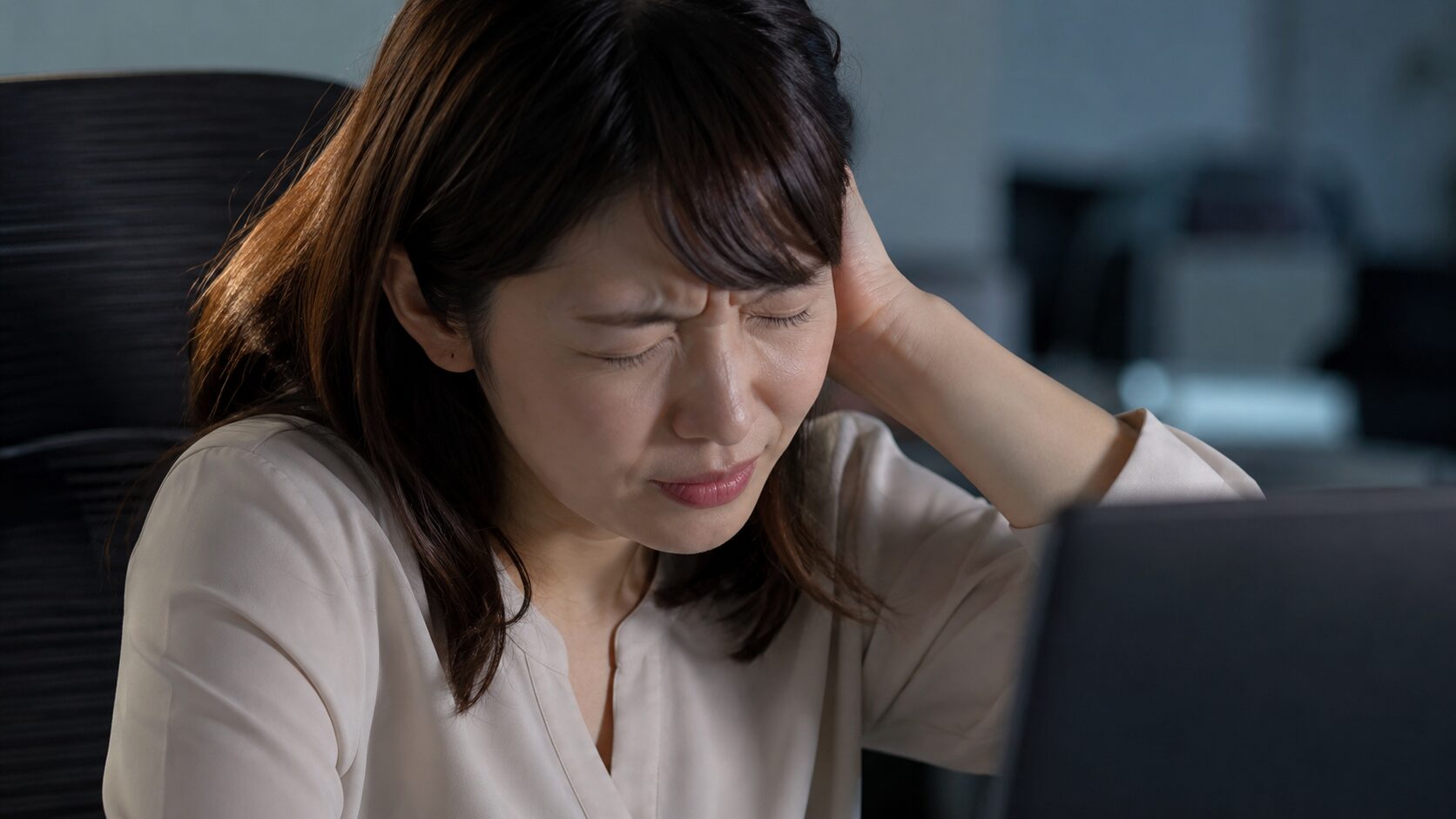 デスクワークで後頭部を押さえてつらそうな女性